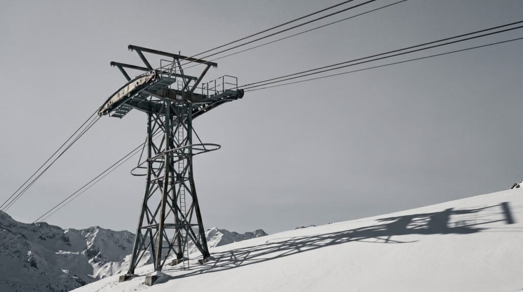 Seilbahnstütze mit Tragseilen vor bedecktem Alpenhimmel