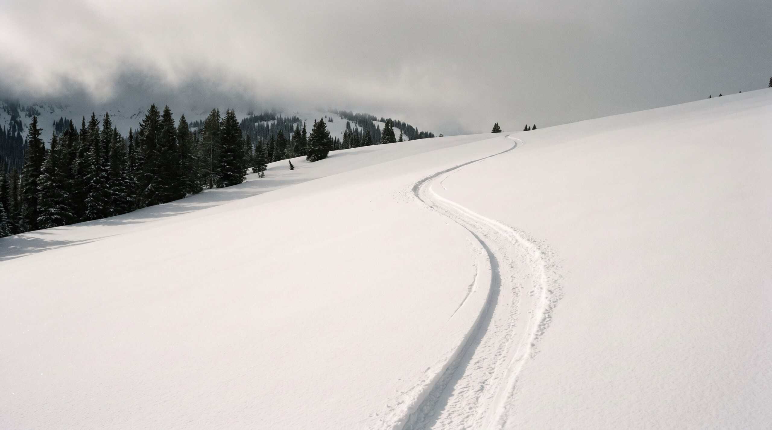 Verschneiter Hang mit einer einzelnen Skispur bei flachem, bedecktem Licht