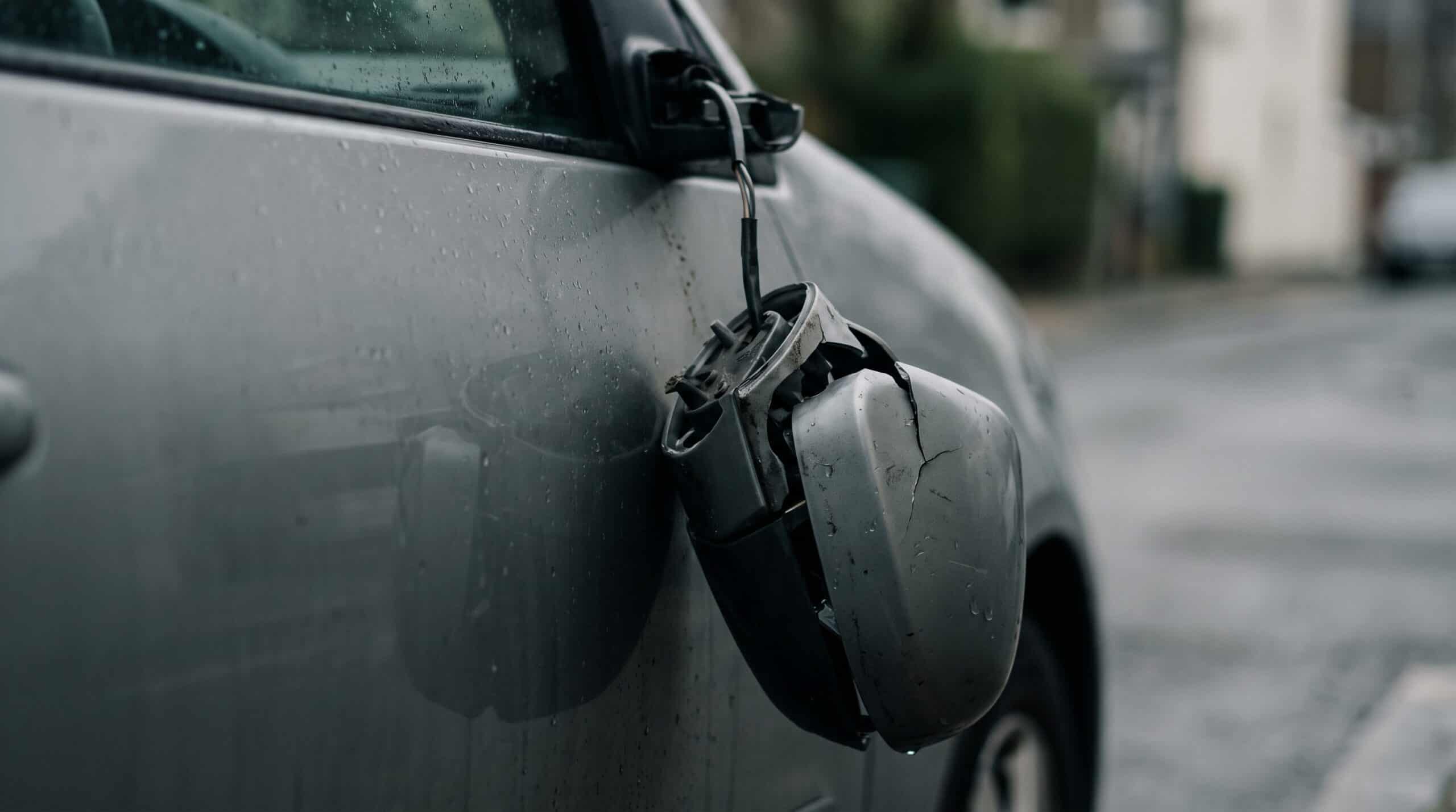 Abgerissener Außenspiegel hängt nach einem Unfall am Kabel an einer Fahrzeugtür